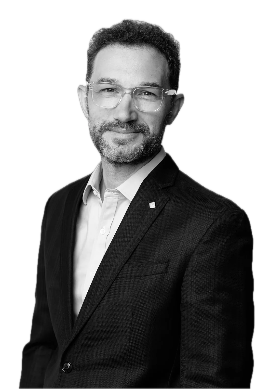 David Martin, in a dark jacket and clear-framed glasses, smiling slightly.