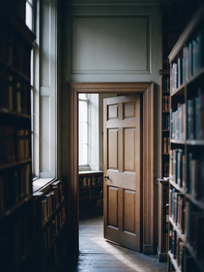 A panelled oak door standing half open in an old library, daylight falling through onto the floor.